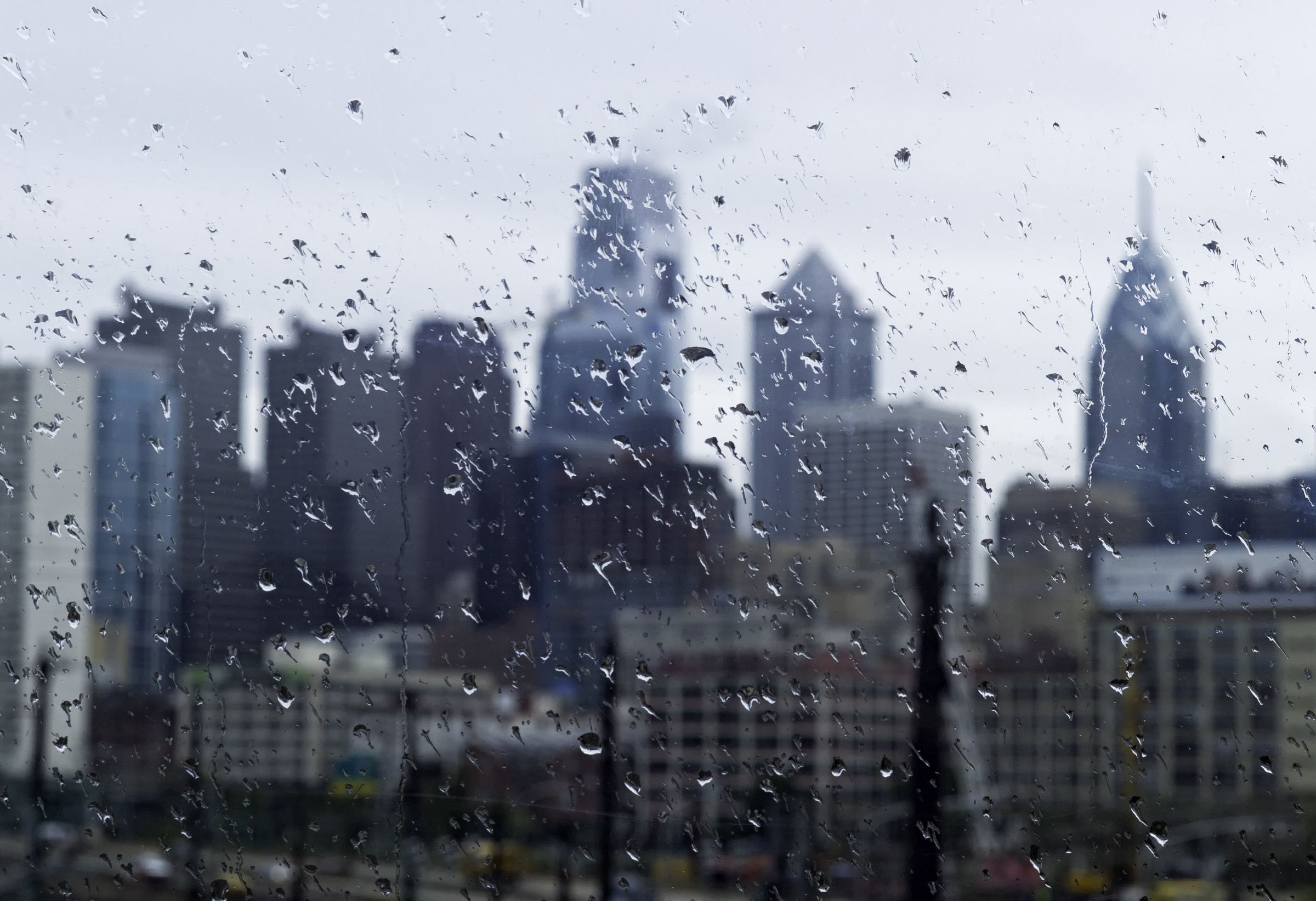 a view out a rain-spattered window, the Philadelphia skyline blurred in the background