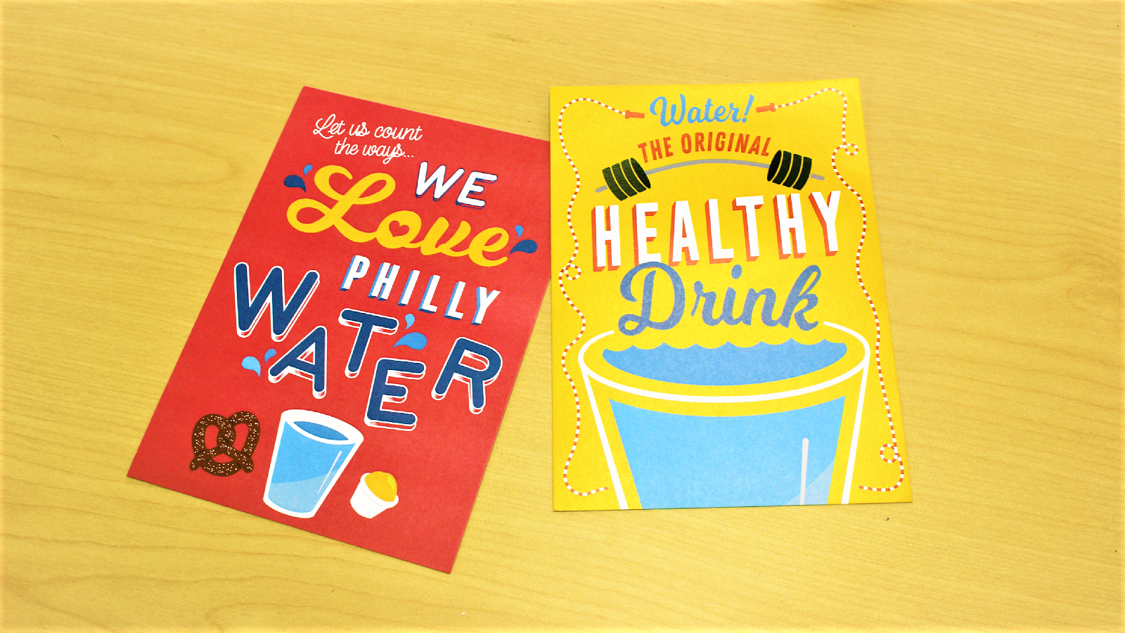 colorful postcards encouraging Philadelphians to drink tap water lay on a light wood table