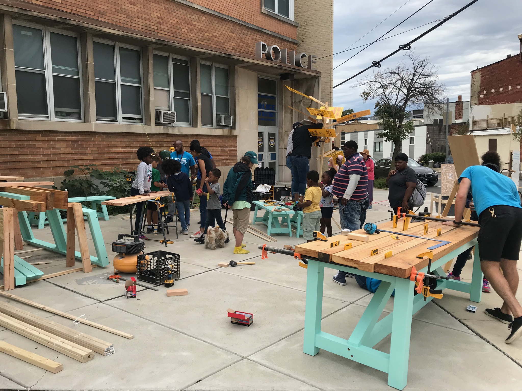Tiny WPA leads community memebers in constructing picnic tables in front of the 16th Police District building