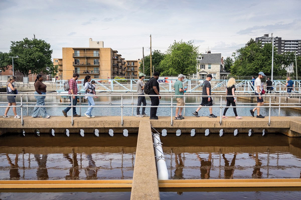 People walking across a walkway over an outdoor water settling basin at one of our treatment plants