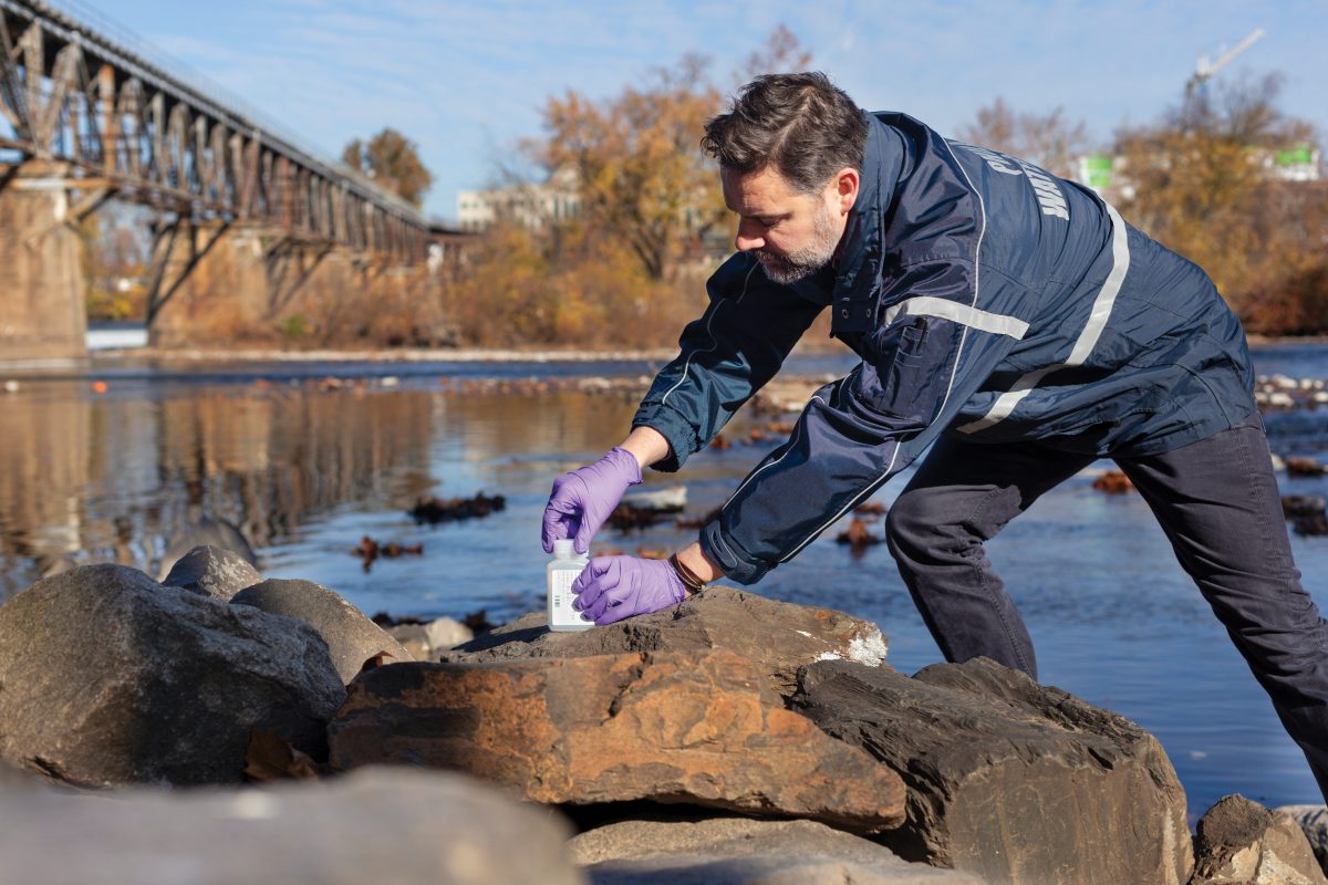 A PWD employee collects a water sample from the river.