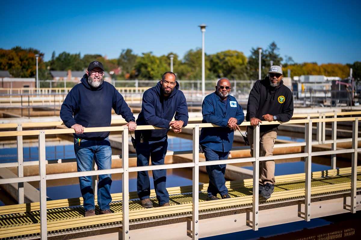 Four PWD staff members leaning on a railing on a walkway over a settling basin at one of our Drinking Water Treatment Plants.