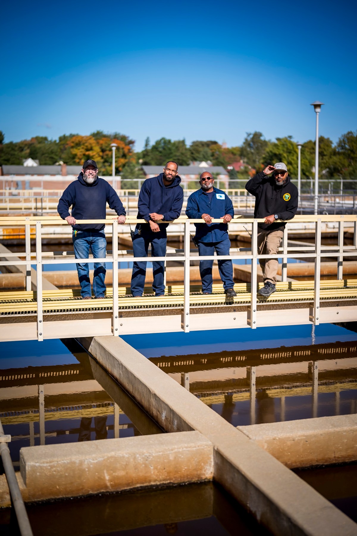 Four PWD staff members leaning on a railing on a walkway over a settling basin at one of our Drinking Water Treatment Plants.