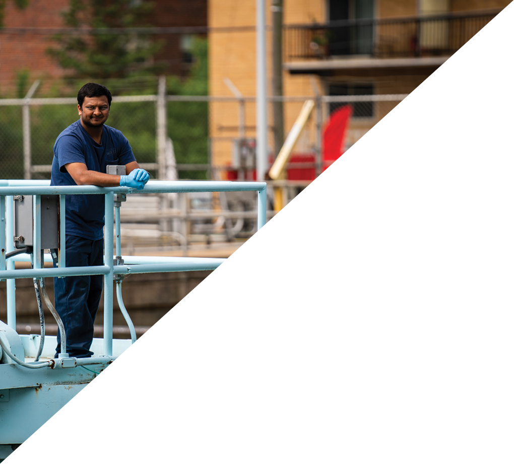 divided into two triangles: The upper/left shows a PWD technician leaning on a railing, looking over a sedimentation basin at one of our treatment plants. The lower/right triangle is empty.