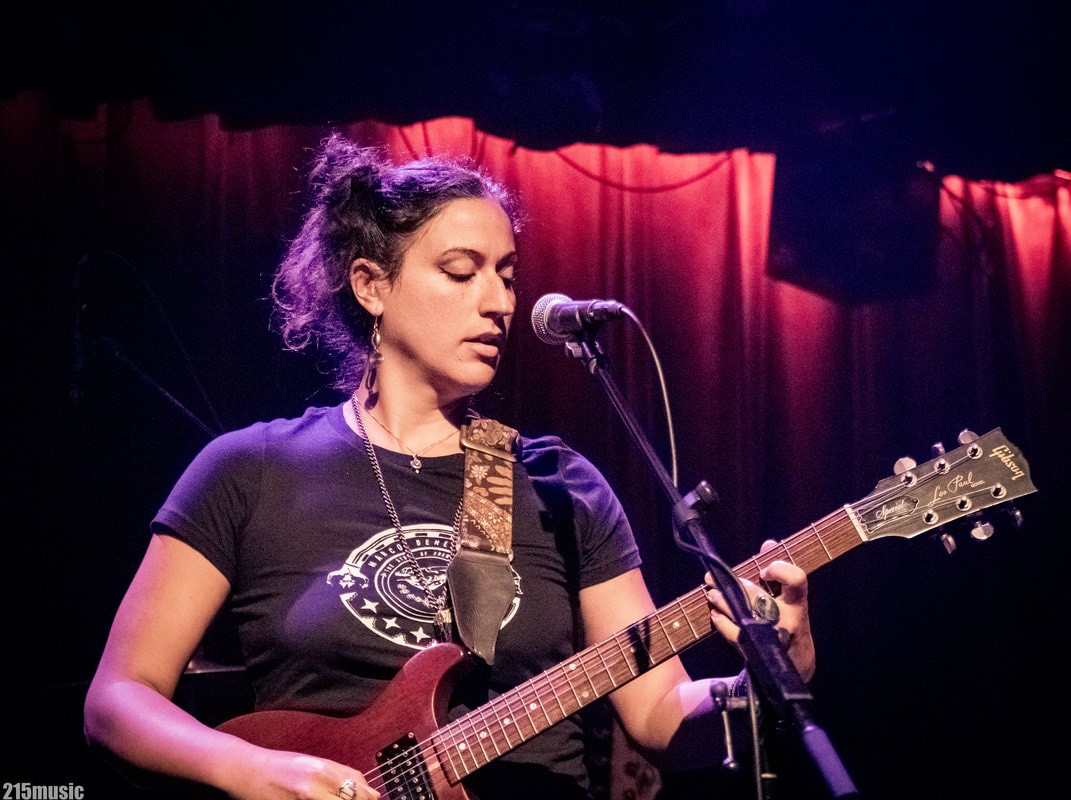 Sonni on stage, playing guitar and singing into a microphone